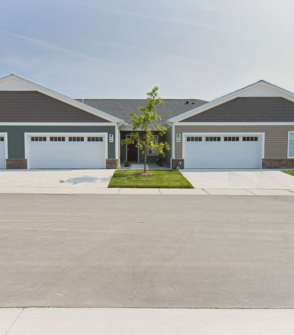 exterior of a condo-style rental home with a beautiful green lawn and blue skies