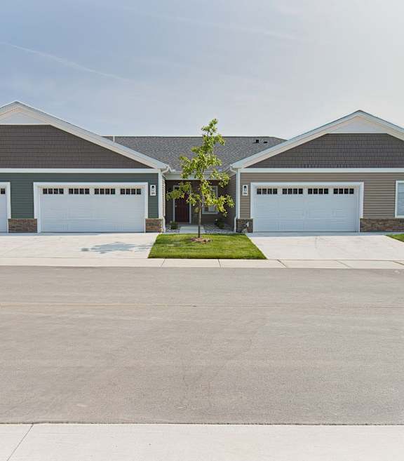 exterior of a condo-style rental home with a beautiful green lawn and blue skies