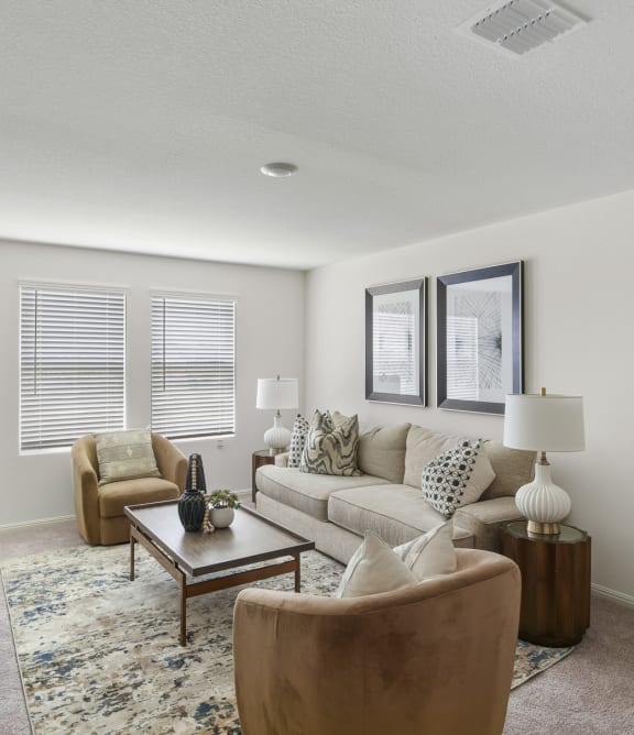 an empty living room with a kitchen in the background