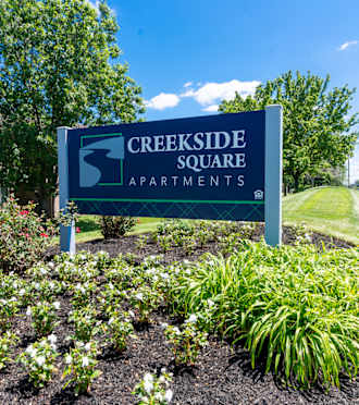 a sign for creekside square apartments in front of a flower garden  at Creekside Square Apartments, Indianapolis, IN 46254