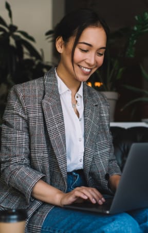 Woman Smiling while Working on Laptop