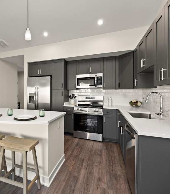 A modern kitchen with dark brown cabinets and stainless steel appliances.