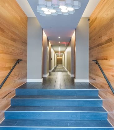 a view down a long hallway with blue stairs and wood walls