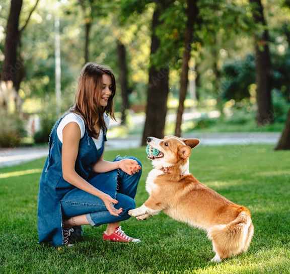 a young woman playing with her dog in a park at The Levi Luxury Apartments, Georgia 30253