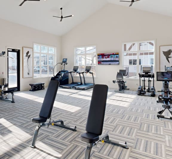 a workout room with weights and chairs in a large room with windows