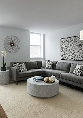 A living room with a grey couch, a coffee table, and a fan on the wall.