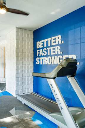 A gym with a blue wall that says "Better. Faster. Stronger."