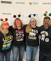 Four people wearing black t-shirts with various prints on them, standing in front of a white background with multiple logos.