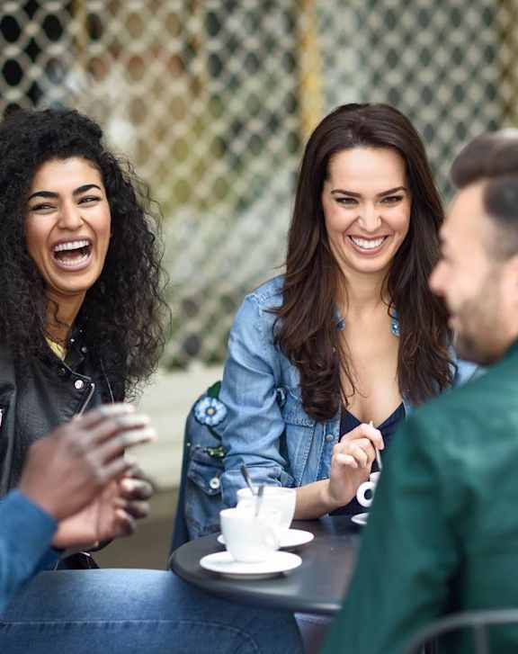 A group of people are sitting around a table, laughing and enjoying each other's company.