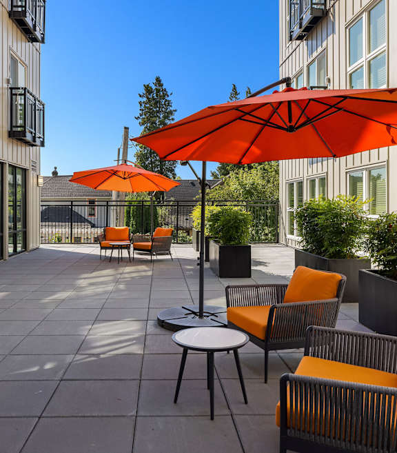A patio with orange chairs and umbrellas.