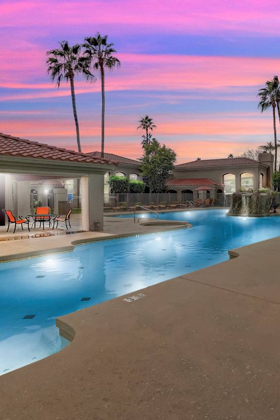 A swimming pool with lounge chairs and palm trees.