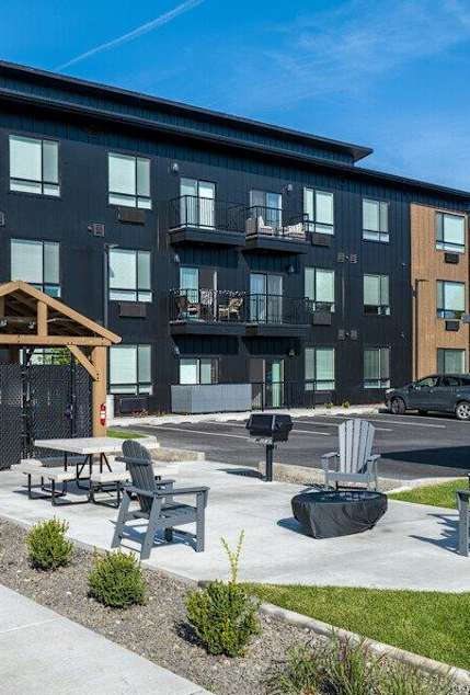 A modern apartment complex with a wooden pavilion and seating area.