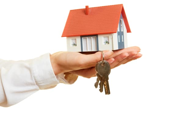A person in a white shirt is holding a small house model and a set of keys. at Yellowstone Landing, Belgrade, MT, 59714