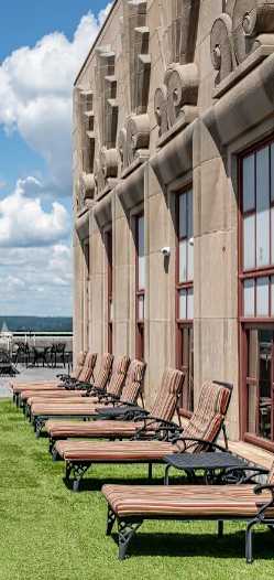 A view of a city from a high vantage point with a row of lounge chairs on the right.