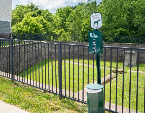 a black wrought iron fence with a green sign on it and a yard behind it
