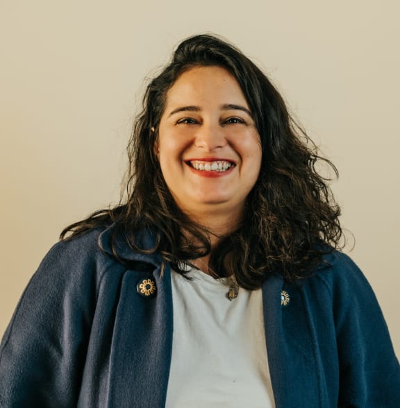 a smiling woman wearing a blue jacket and a white shirt