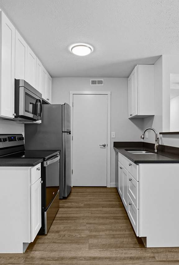 A modern kitchen with white cabinets and a black countertop.