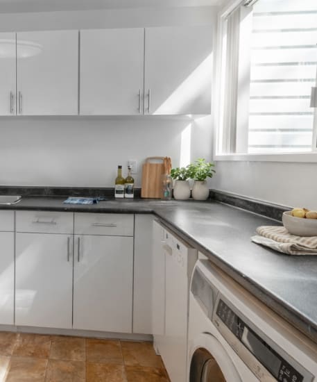 A modern kitchen with a stainless steel refrigerator and wooden flooring.