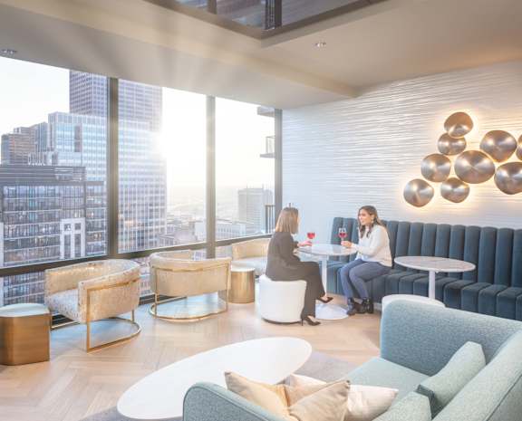 Two women sitting at a table in a brightly lit room with a city view at 365 Nicollet, Minneapolis, 55401
