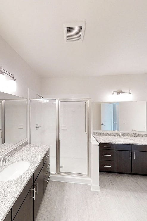 a bathroom with a shower and sinks and a mirror