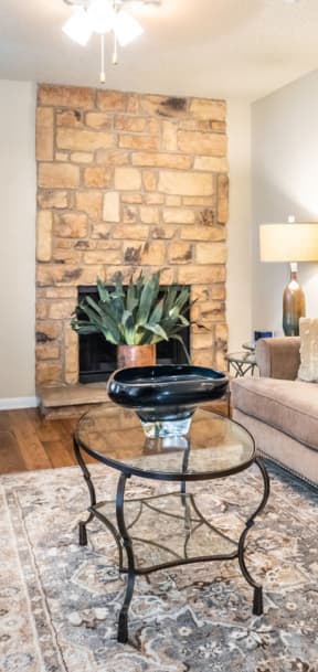 a living room with a couch and a stone fireplace at Summit Ridge Apartments, Texas
