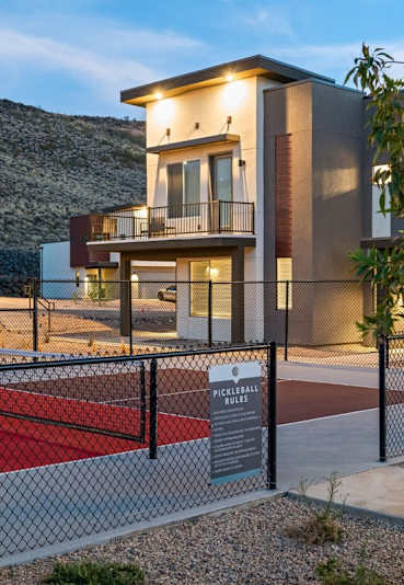 A tennis court is located in front of a building with a sign that reads "Pickleball".