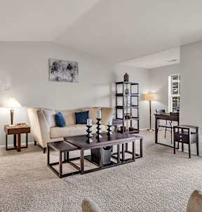 A living room with a couch, chair, and a table with a vase on it.
