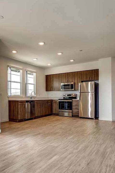 A kitchen with a refrigerator, oven, and sink is visible through an open door.