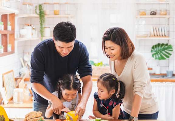 A family of four is preparing a meal together in the kitchen.