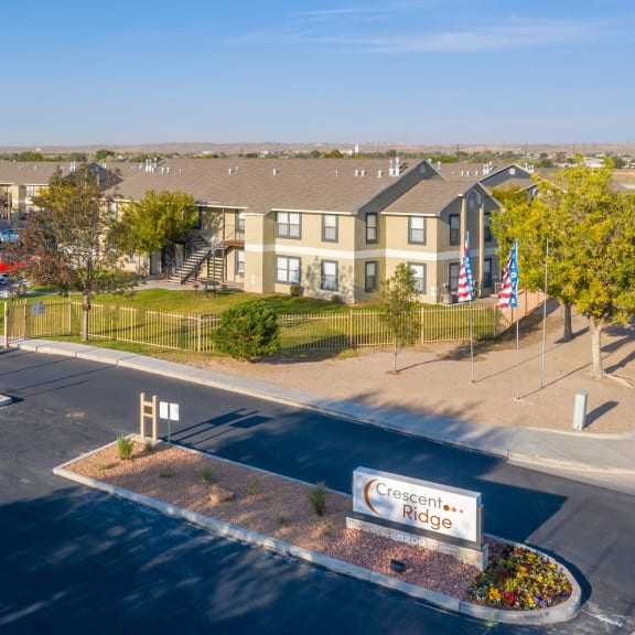 an aerial view of an apartment complex with flags and a parking lot