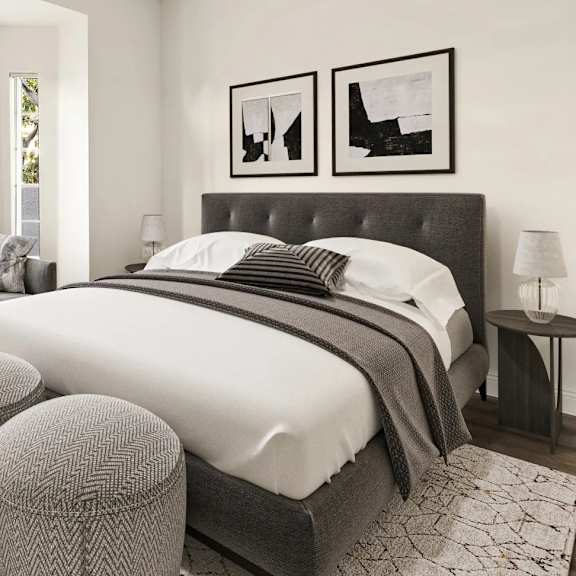 A bedroom with a large bed and two ottomans.