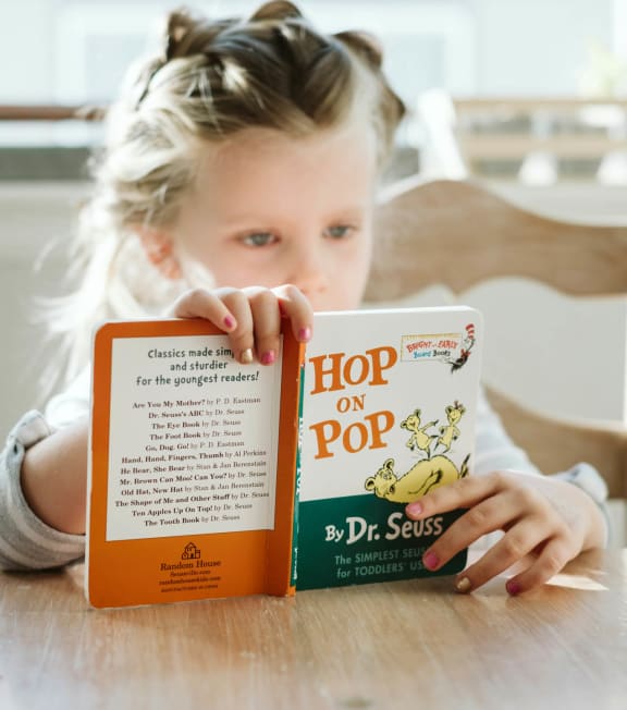 a young girl reading a book titled hop on top