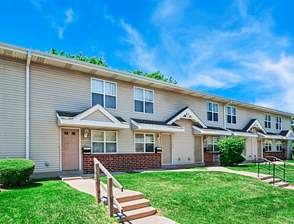A row of houses with green lawns and a clear blue sky.