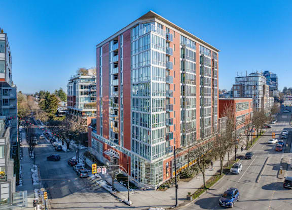 A tall red and white building is in the middle of a city street.