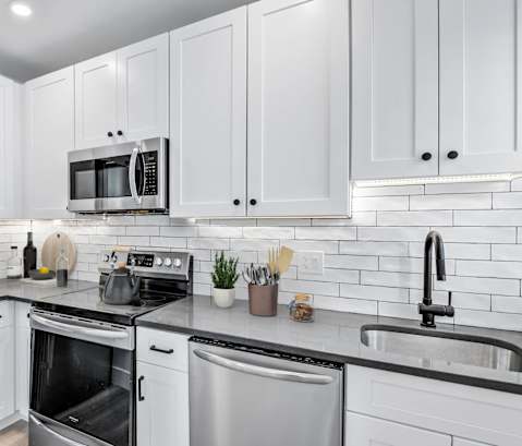 a white kitchen with stainless steel appliances and white cabinets