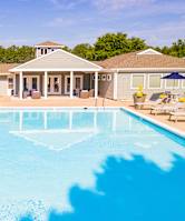 A large swimming pool with sun loungers and a building in the background.