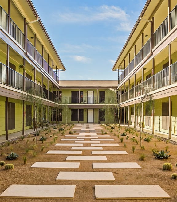 a courtyard between two buildings with plants in the middle