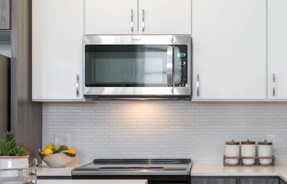 A modern kitchen with a white table and grey cabinets.