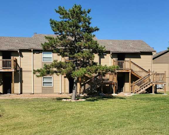 Willow Creek Apartments - Exterior view of the apartment complex surrounded by green lawns and trees.
