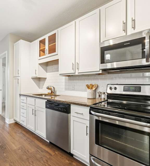 A modern kitchen with white cabinets and stainless steel appliances.