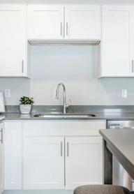 A modern kitchen with white cabinets and stainless steel appliances.