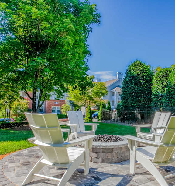 Two chairs are placed around a fire pit in a grassy area.