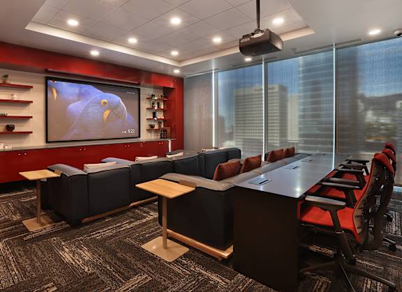 A conference room with a large screen and a view of the city.