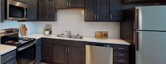 a kitchen with black cabinets and stainless steel appliances and a wood floor