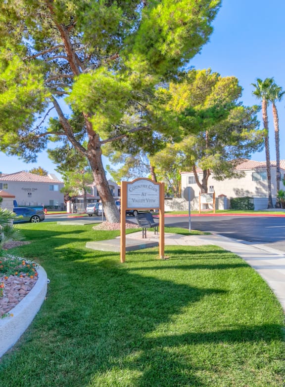 a street with a sign on the grass next to a sidewalk