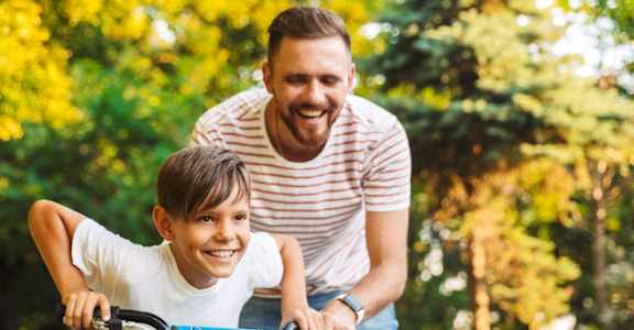 Father Helping Teach Son How to Ride Bike