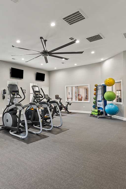a workout room with treadmills and a tv