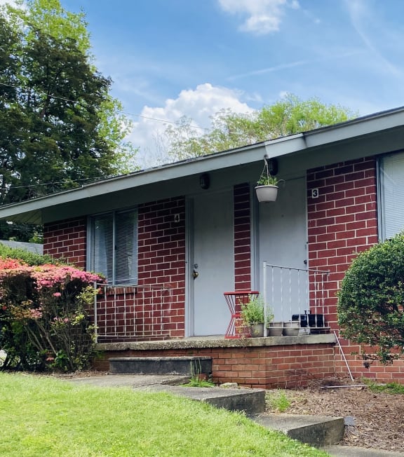 the front of a brick house with a porch and a lawn