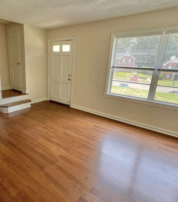 an empty living room with a hard wood floor and a staircase