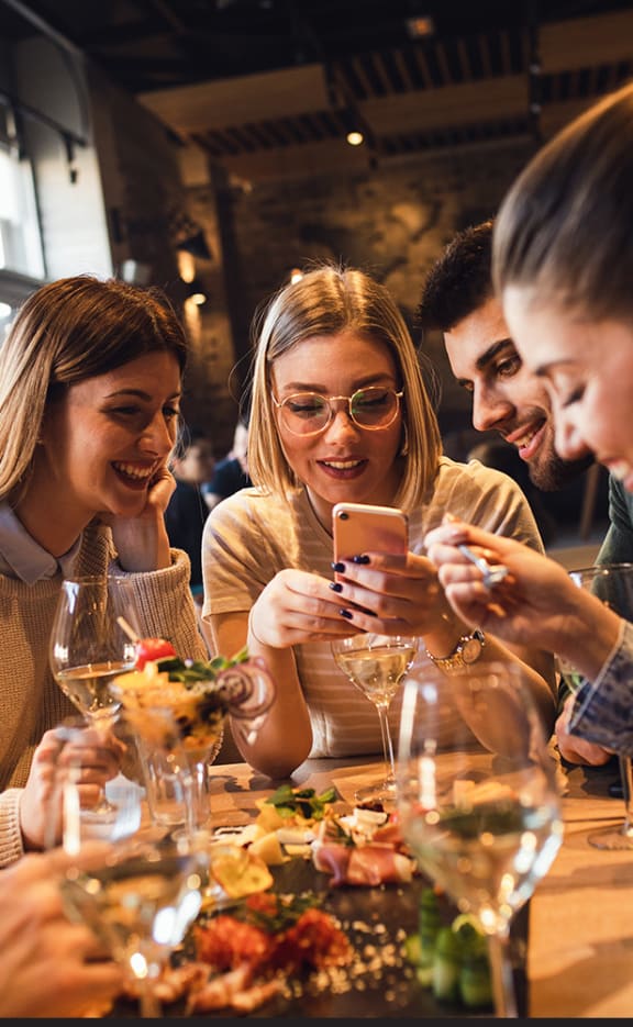 a group of people sitting at a table in a restaurant looking at their cell phones